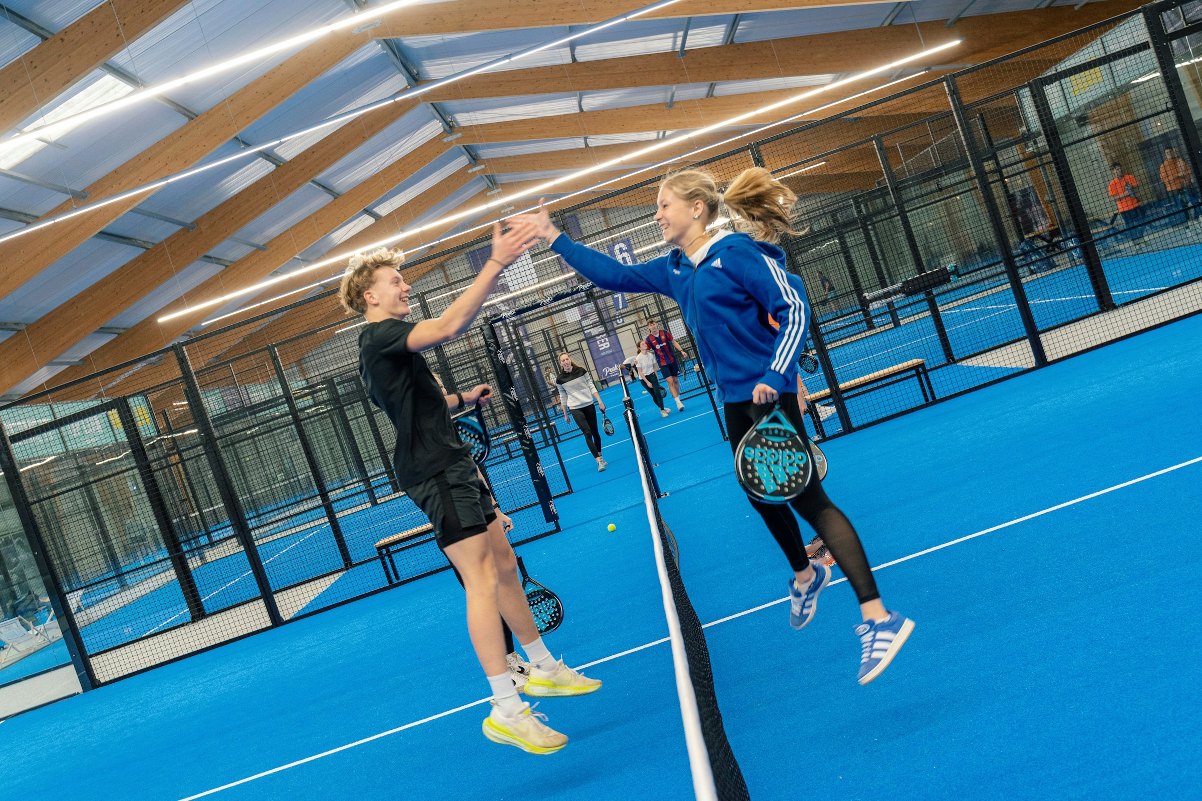 Twee padelspelers geven elkaar een high five boven het net